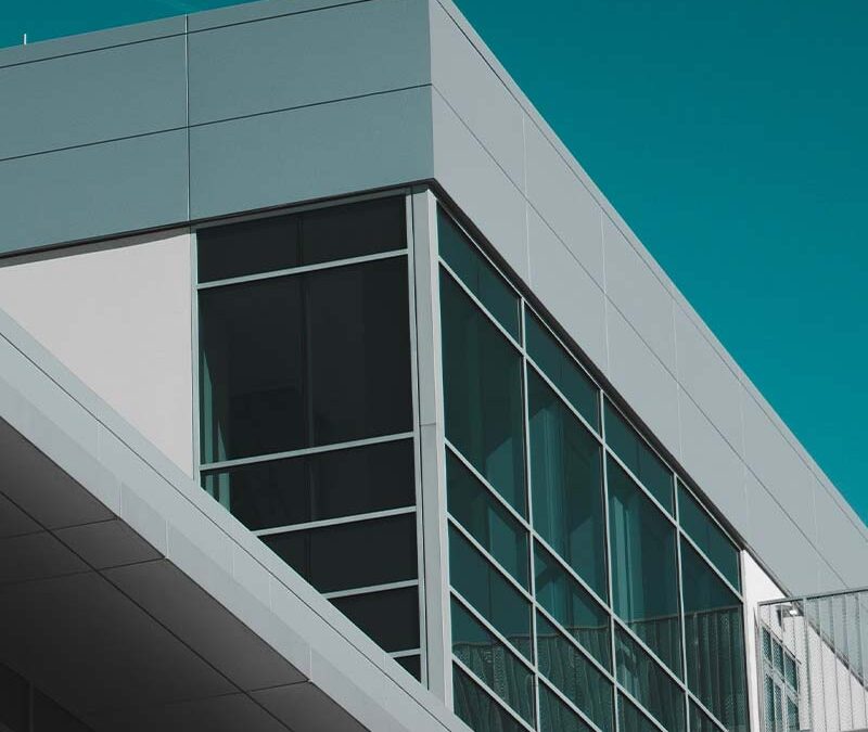 Angle d’un bâtiment tertiaire avec large baie vitrée et ciel dégagé.